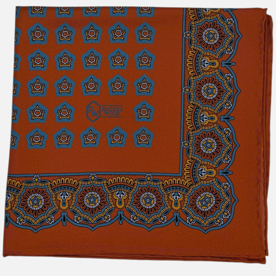 Tangerine colour silk pocket square with royal blue and tangerine star medallions repeating across the silk.