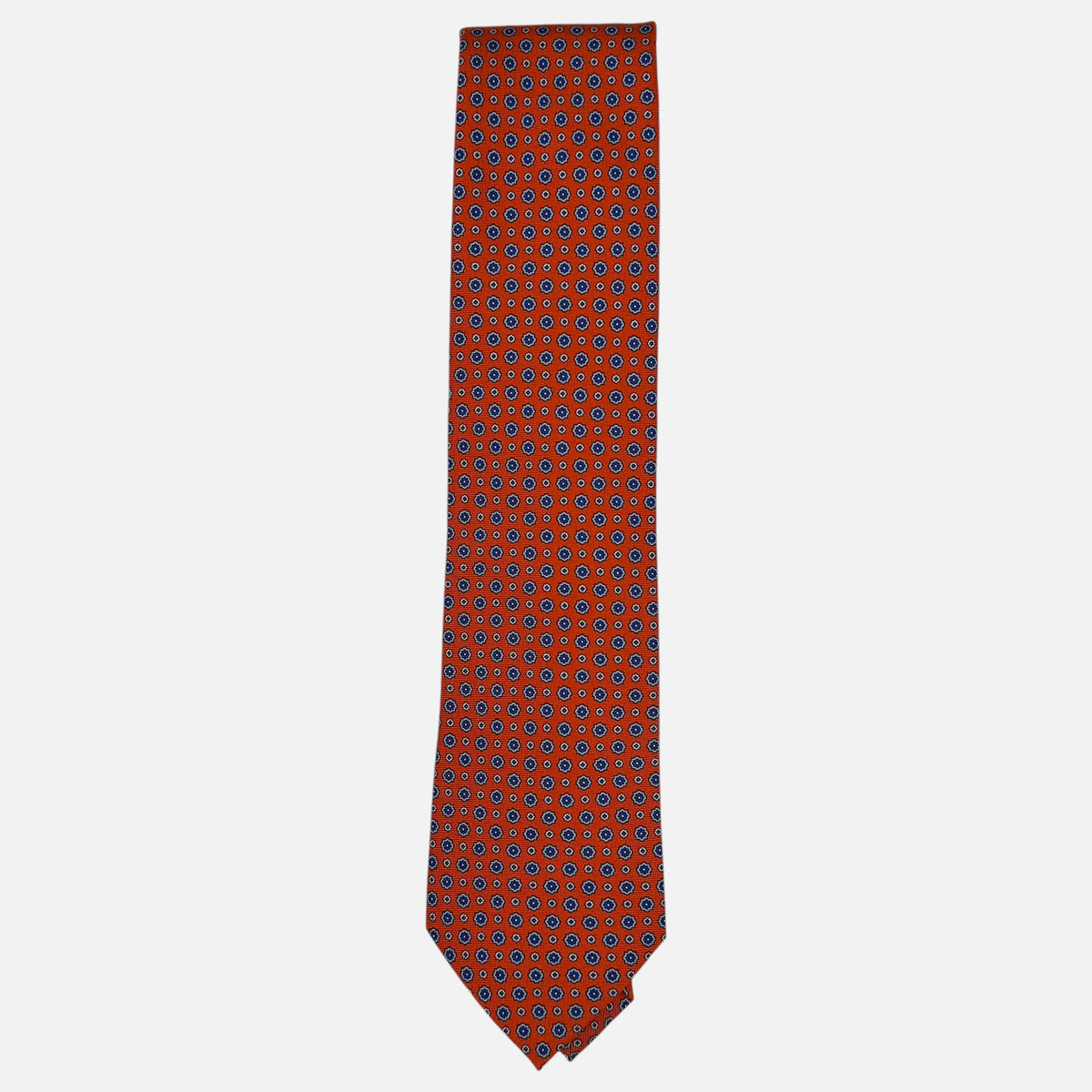 A tangerine coloured neck tie with repeating rosette patterns across the silk.