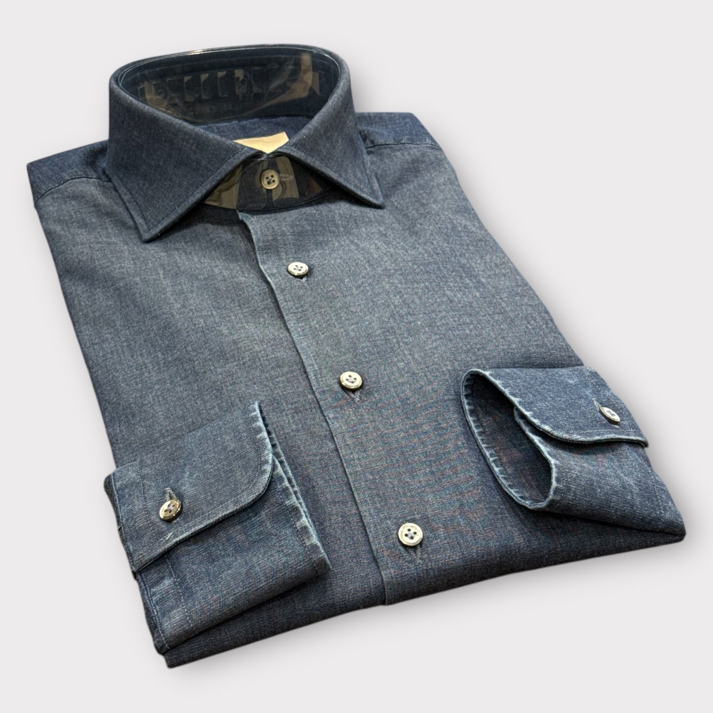 Folded blue denim shirt on a light gray background