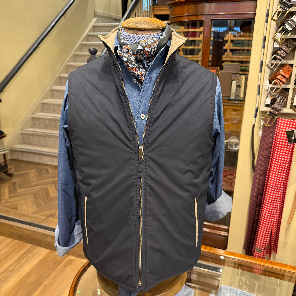 Mens Navy Reversible gilet, on the navy side on a mannequin inside a Rhodes wood store