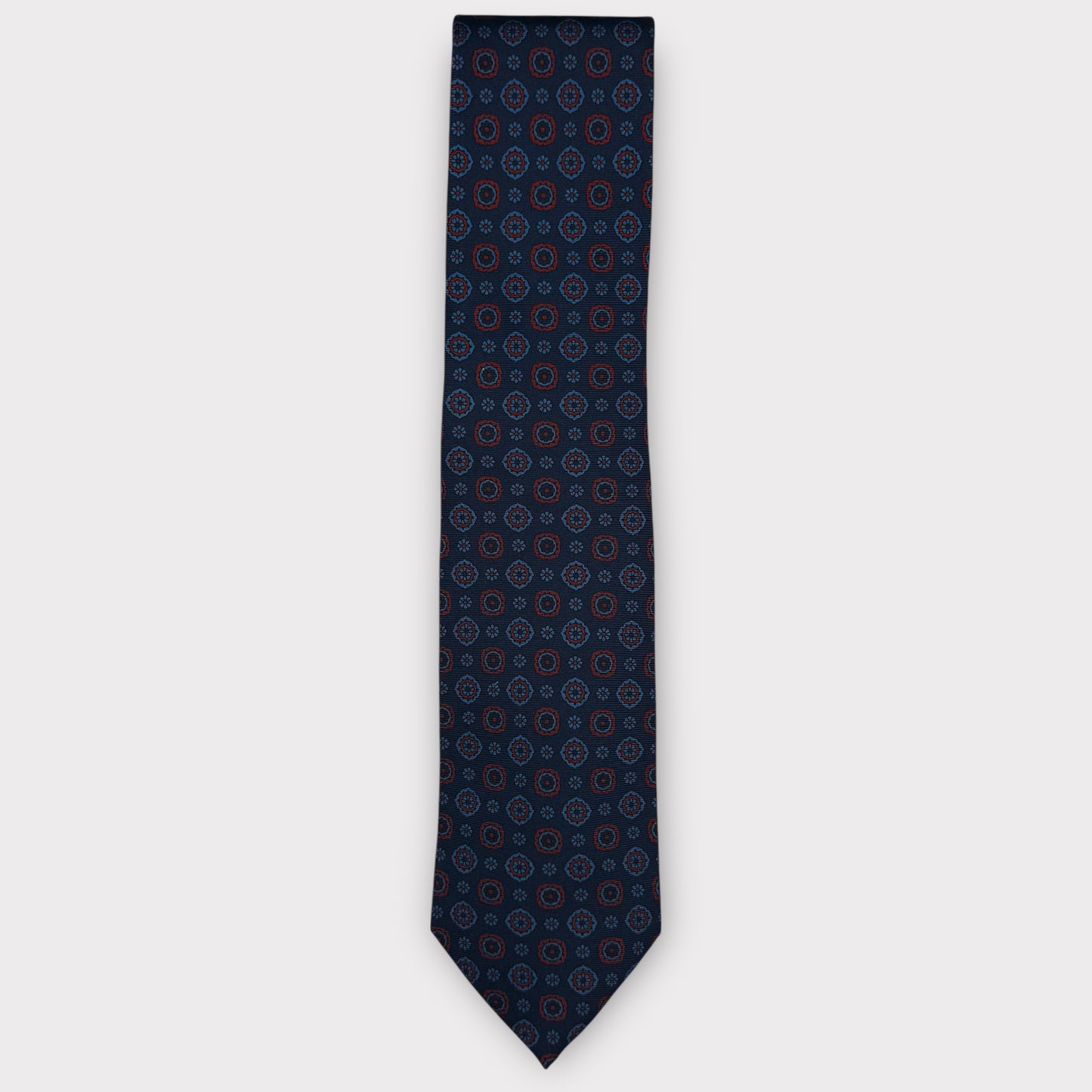Classic silk necktie, printed in England, with a 9cm blade and 150cm length, laid flat against a plain background