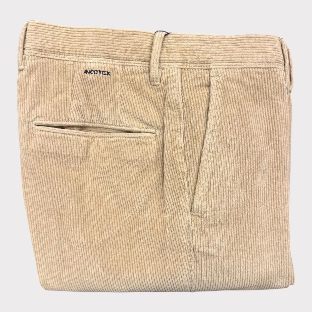 Folded beige corduroy pants with a visible brand logo on a light gray background