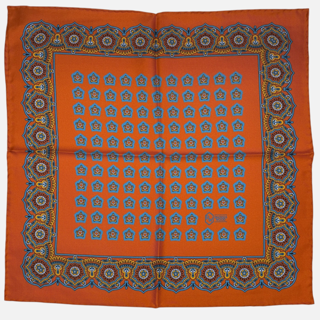 Tangerine colour silk pocket square with royal blue and tangerine star medallions repeating across the silk. 