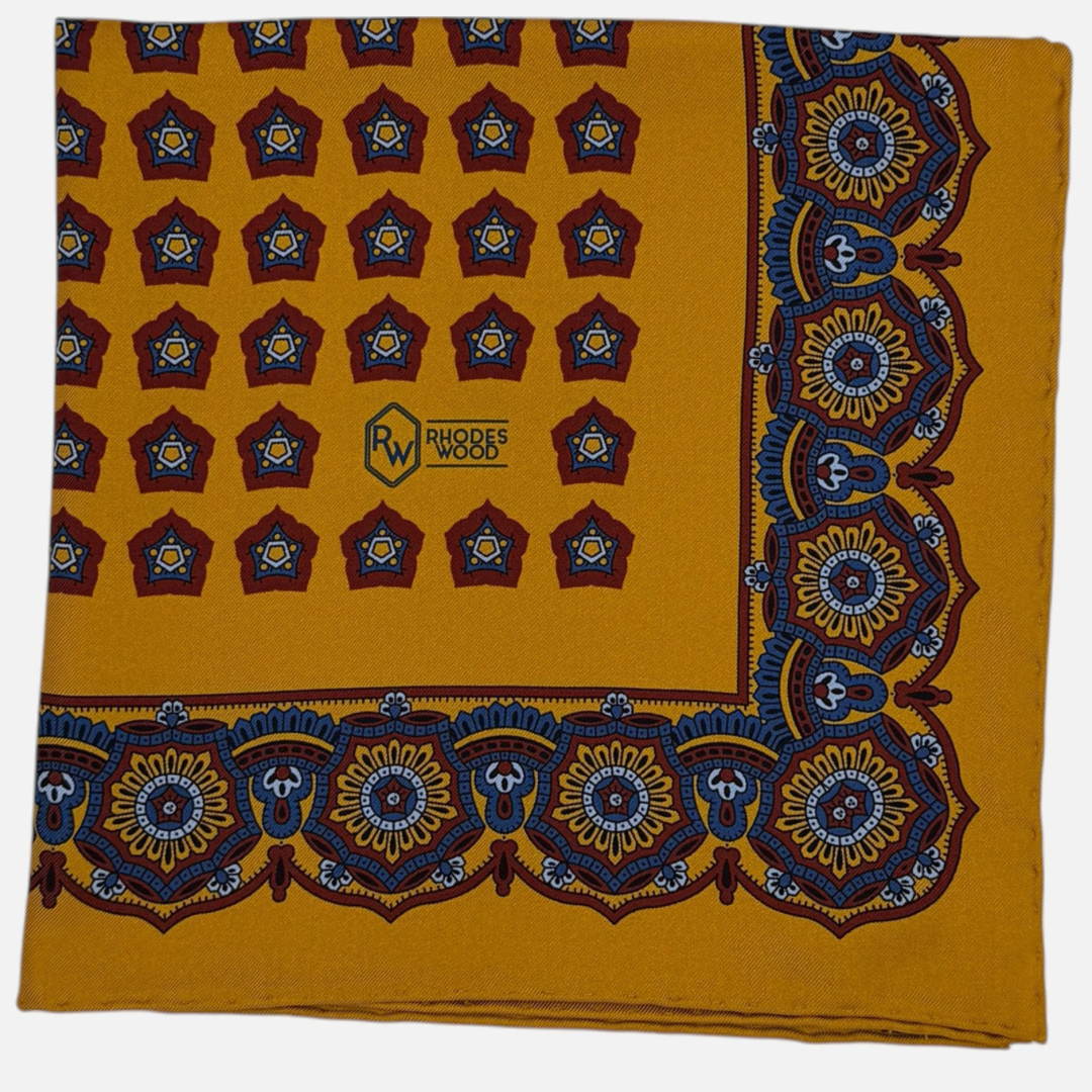 A gold pocket square with red star medallions repeating across the silk. 