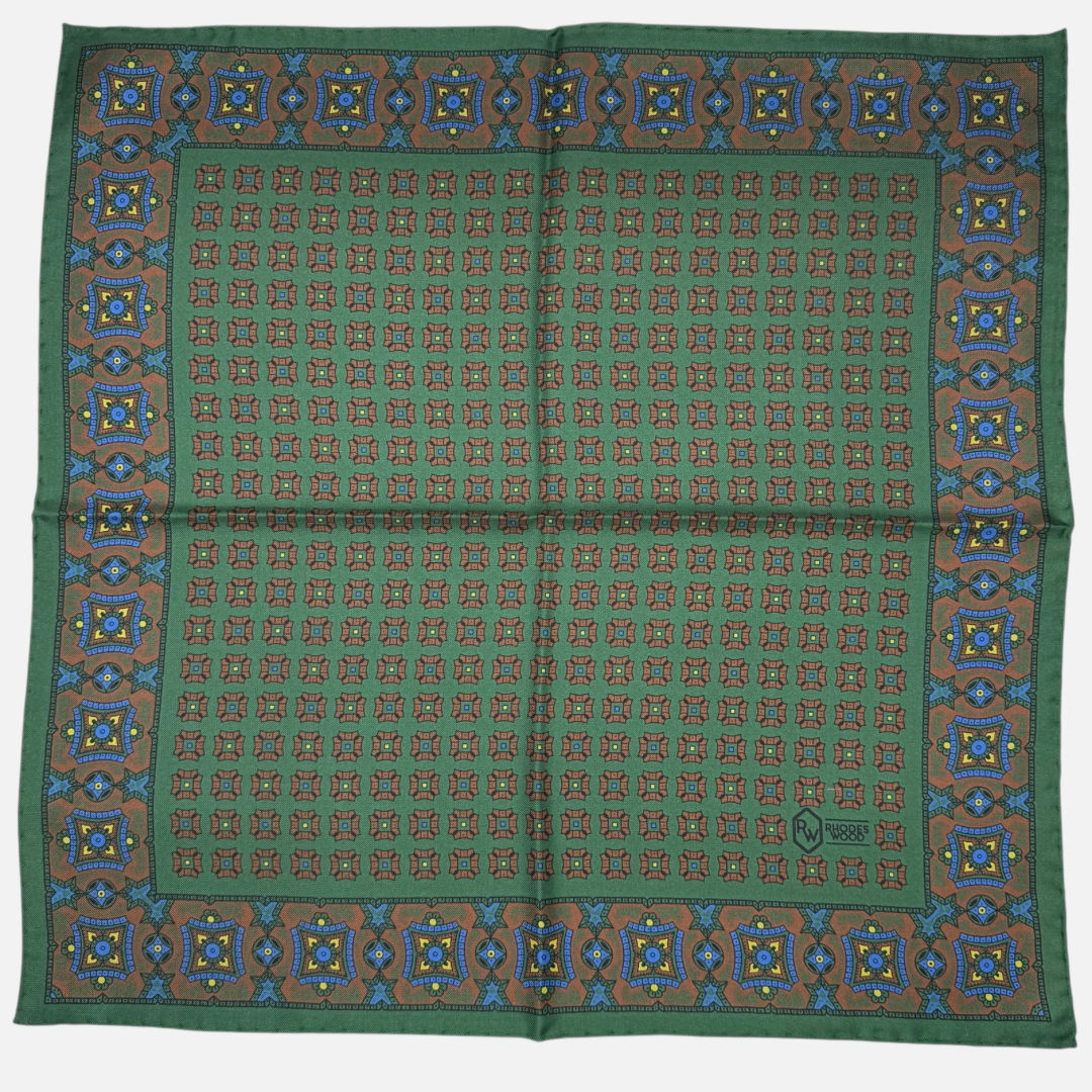 A green pocket square with brown mosaic repeating across the silk. 