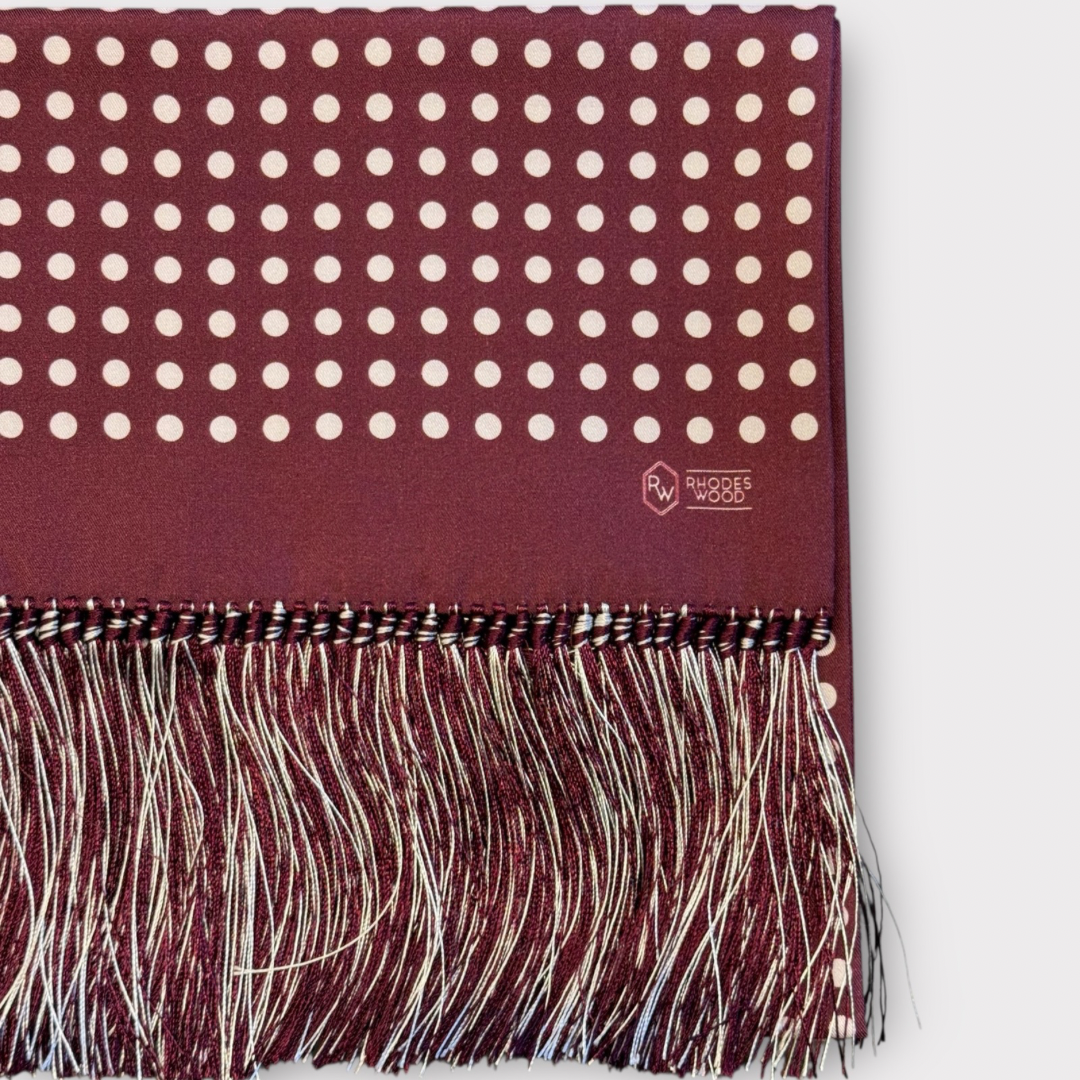 Maroon scarf with white polka dots and fringe on a white background