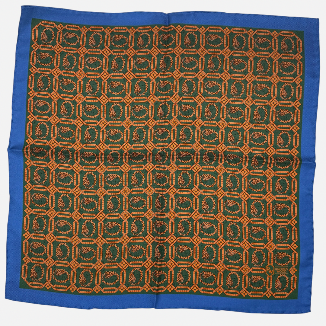 Green & orange octagon paisleys repeating across the silk pocket square with a blue border. 