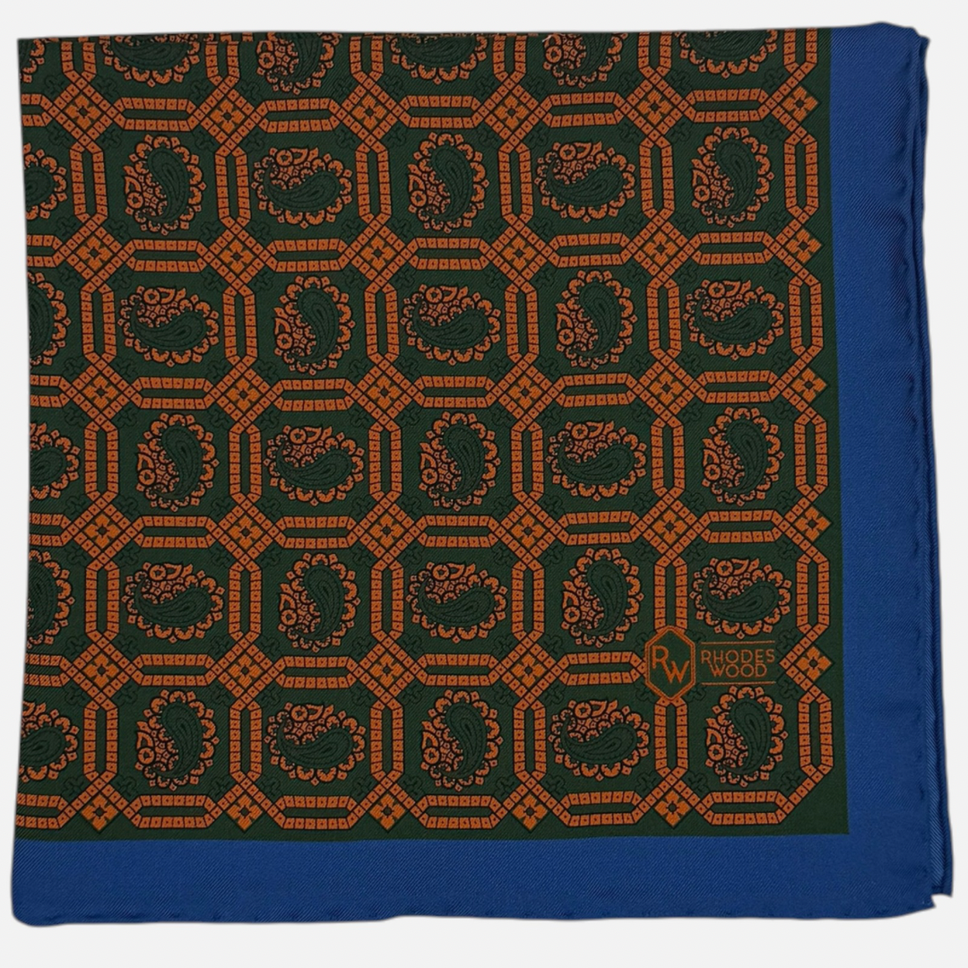 Green & orange octagon paisleys repeating across the silk pocket square with a blue border. 