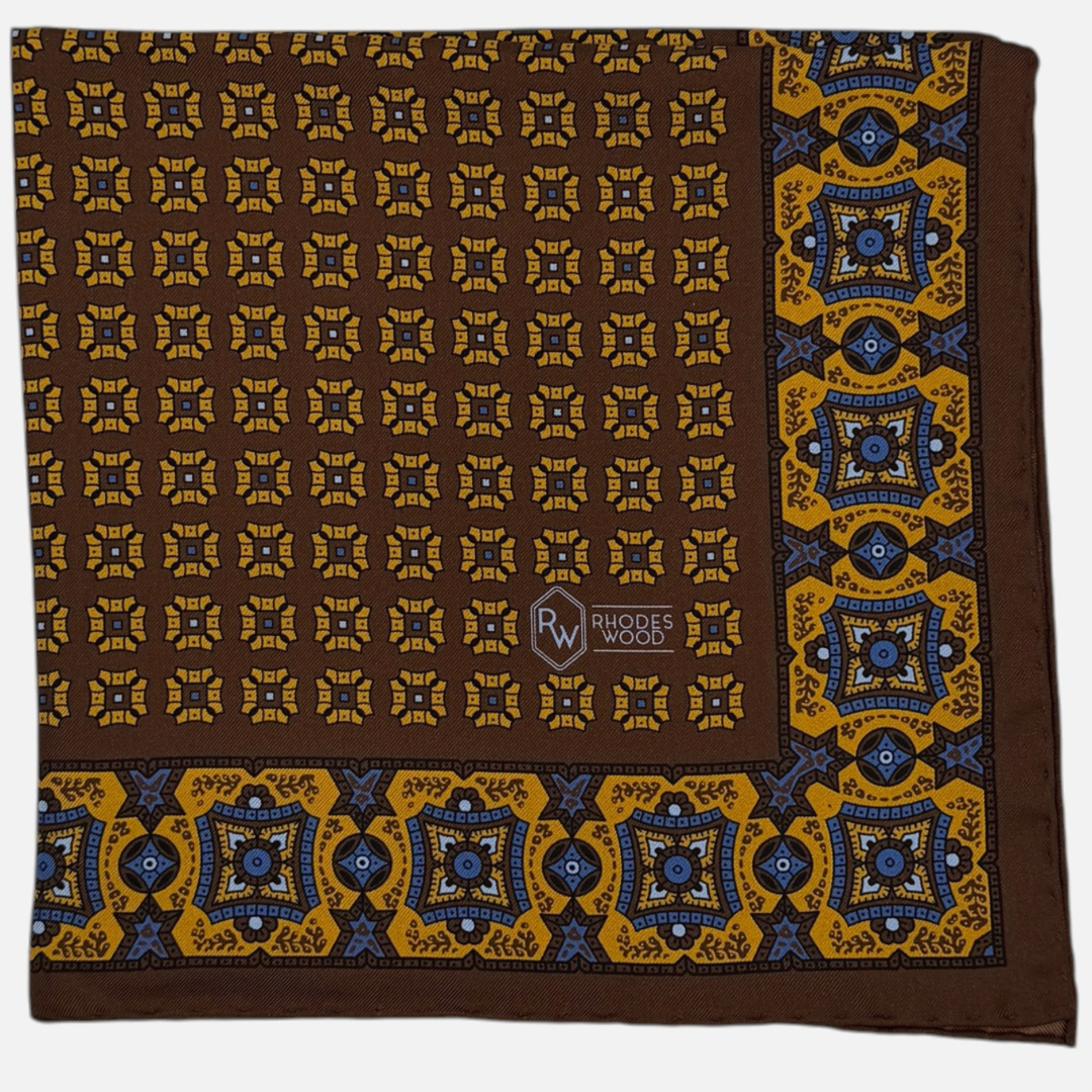 A brown pocket square with yellow mosaic pattern repeating across the silk.