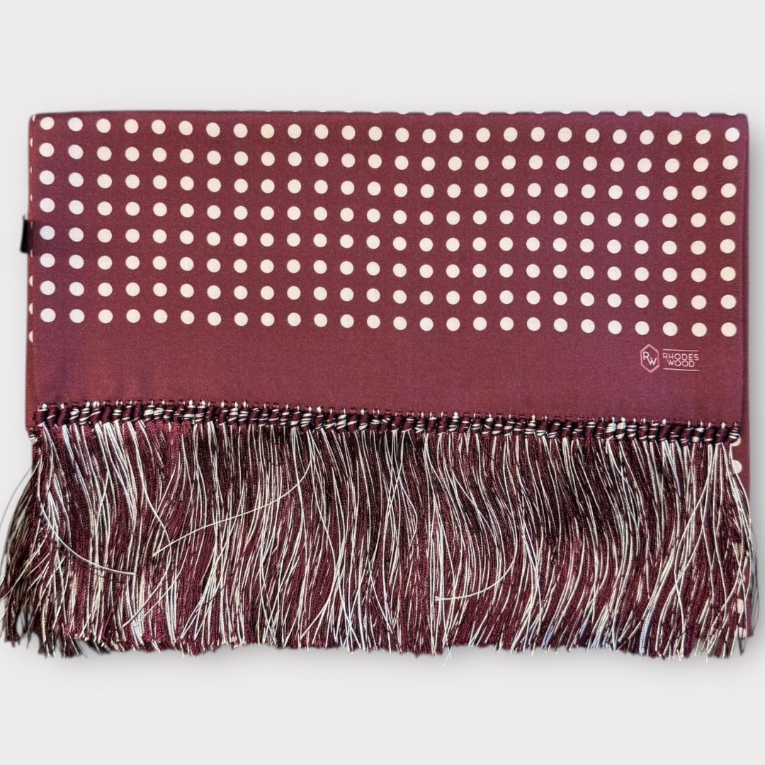 Maroon scarf with white polka dots and fringe on a white background