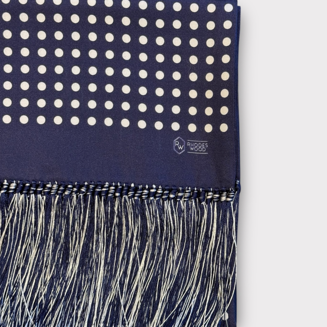 Navy blue scarf with white polka dots and fringe on a white background