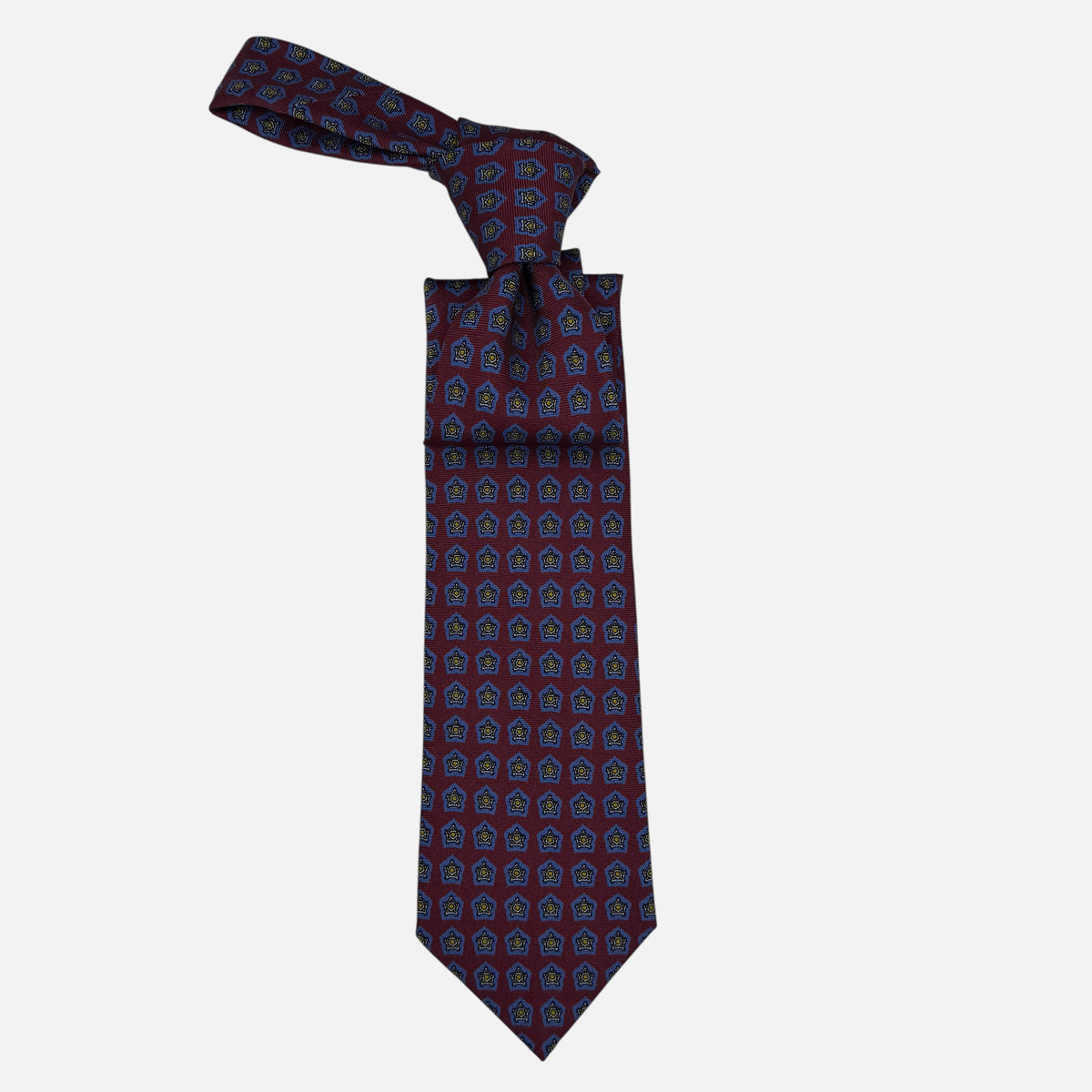 A oxblood neck tie with blue star medallions repeating across the silk.