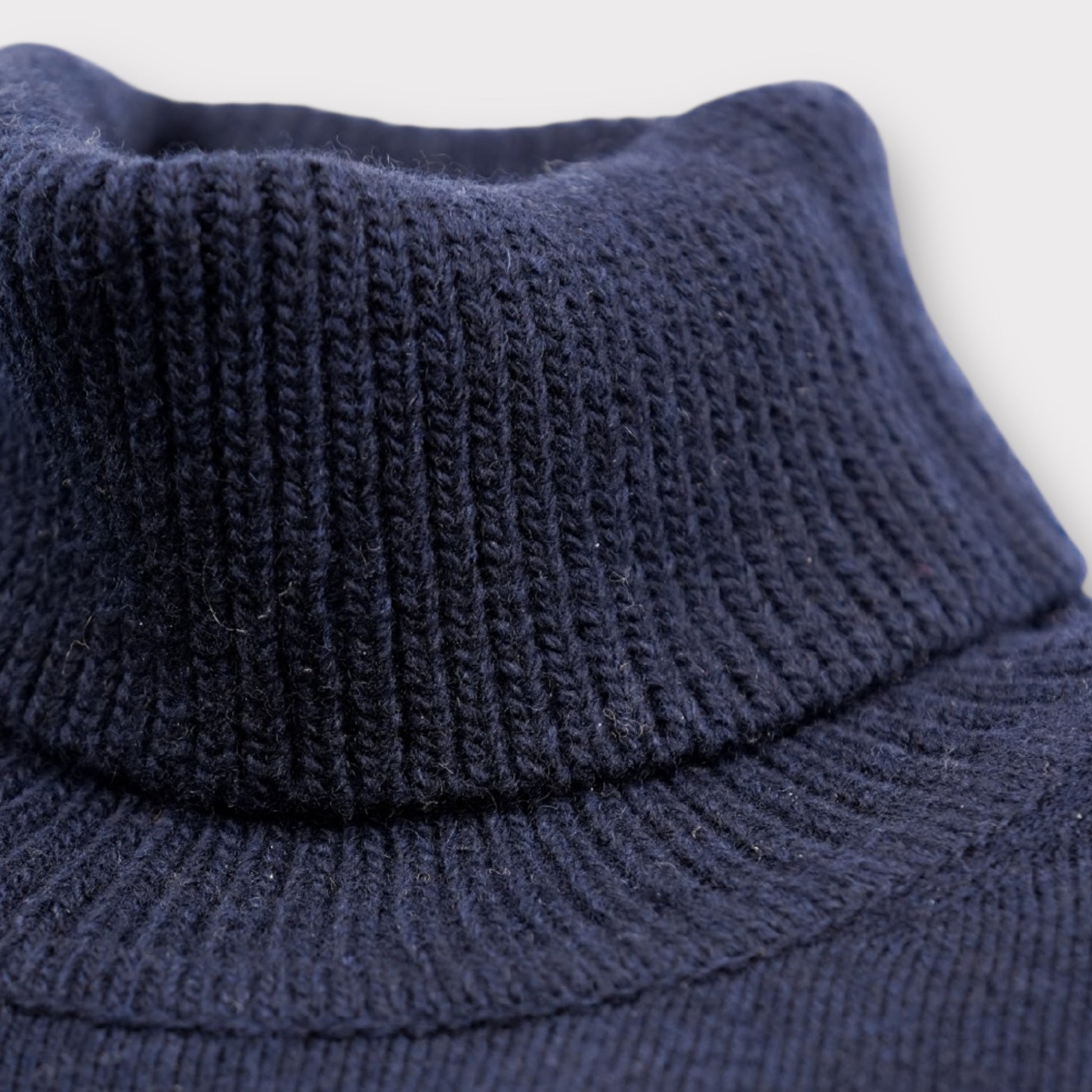 Close-up of a navy blue knitted sweater with a high collar on a light gray background