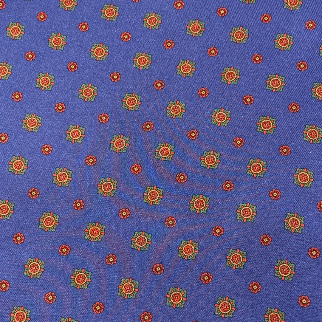 Patterned fabric with red and green floral design on a blue background