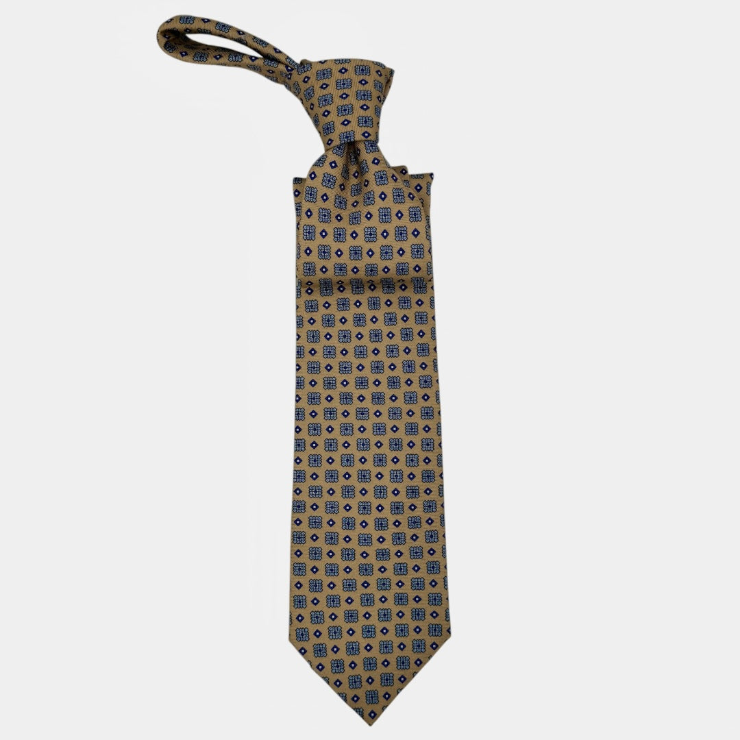 A camel base colour neck tie with navy medallions repeating. 