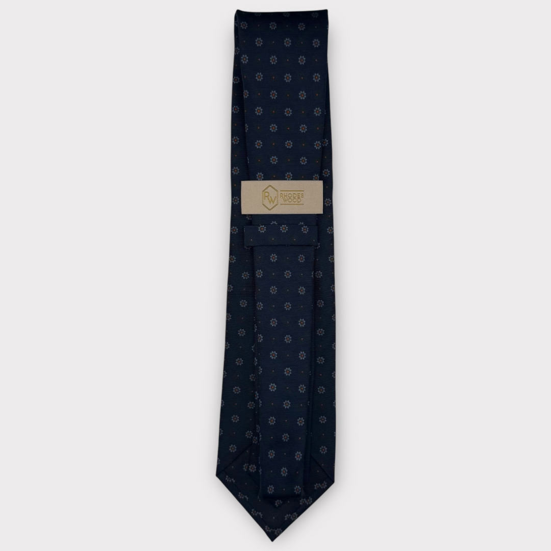 Classic silk necktie, printed in England, with a 9cm blade and 150cm length, laid flat against a plain background