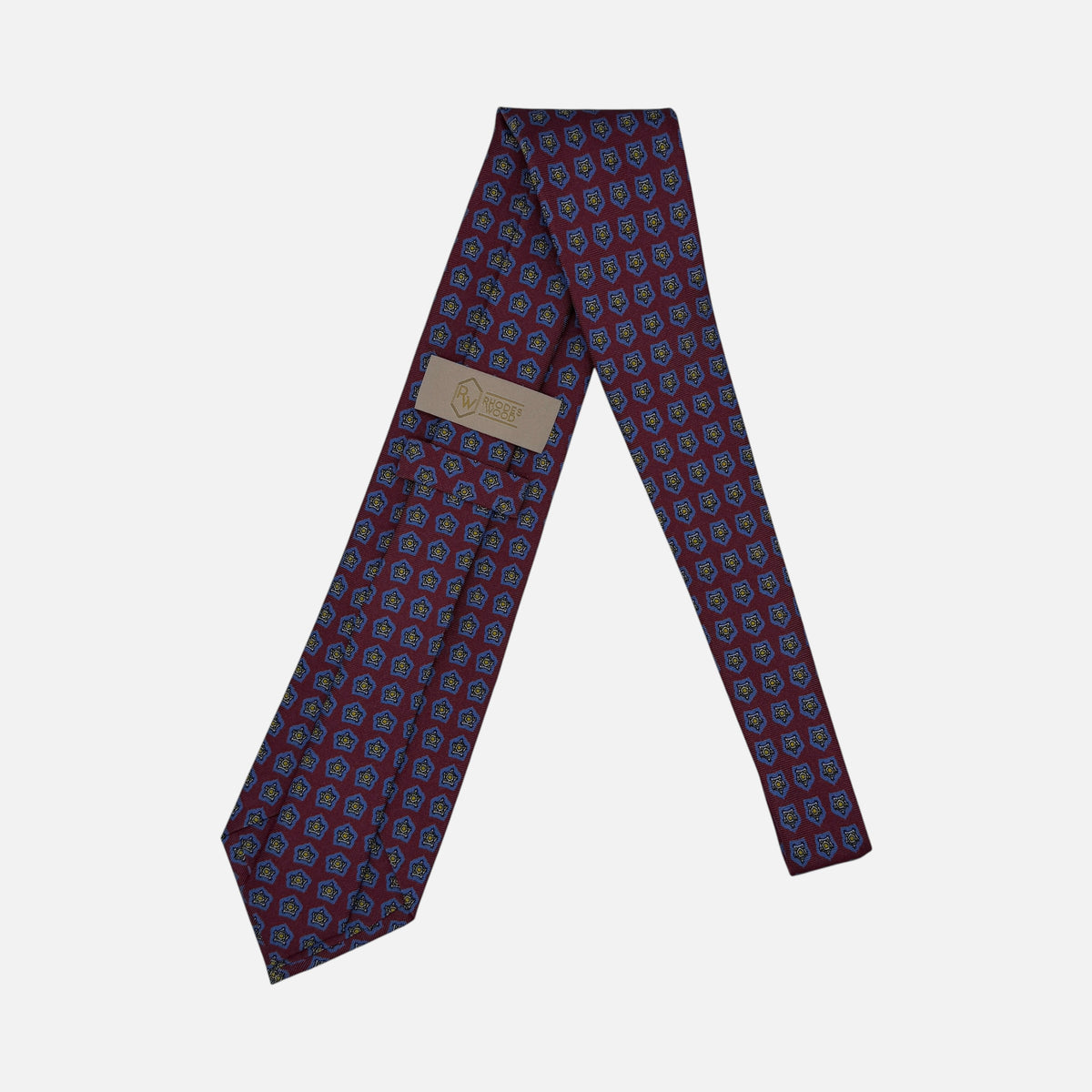 A oxblood neck tie with blue star medallions repeating across the silk.