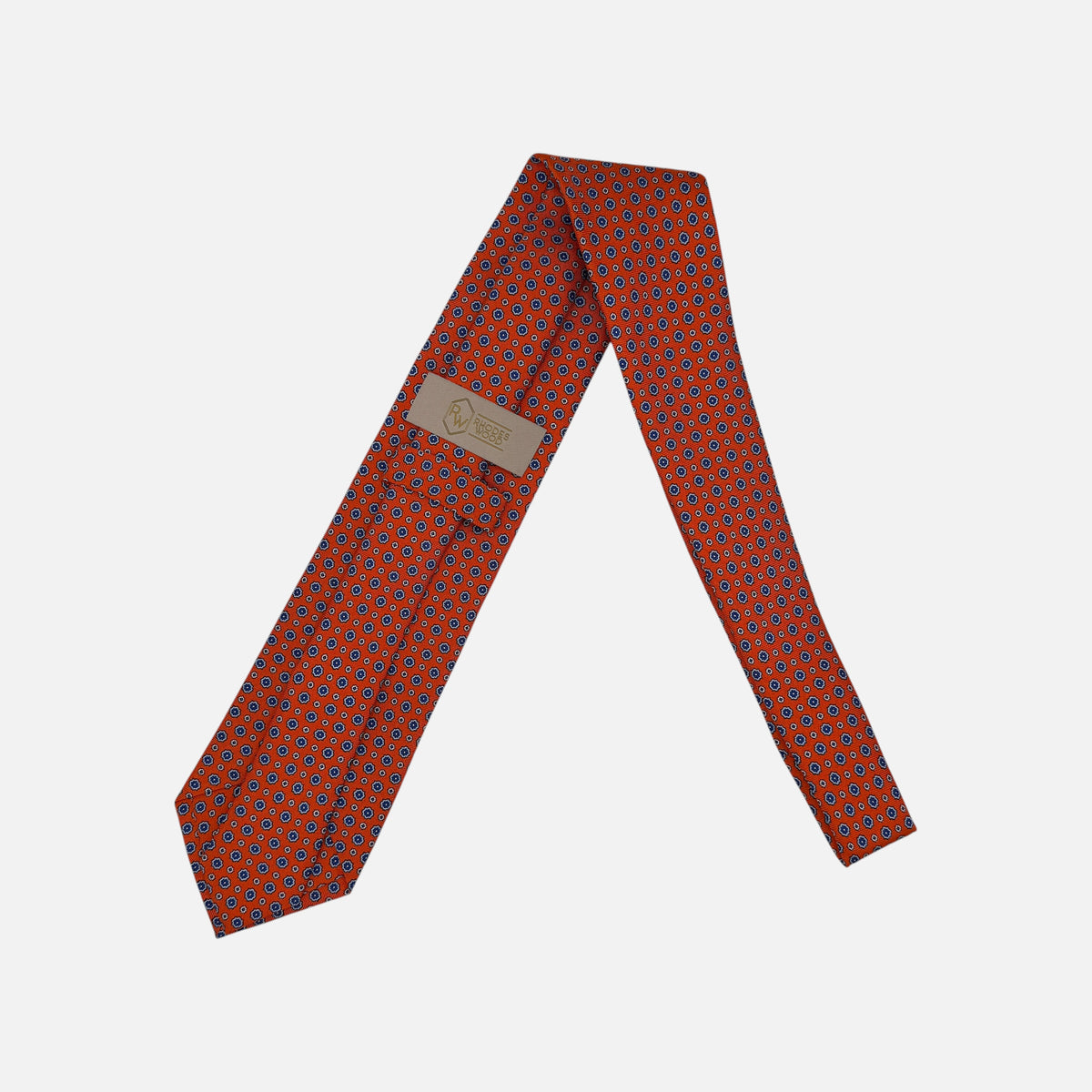 A tangerine coloured neck tie with repeating rosette patterns across the silk.