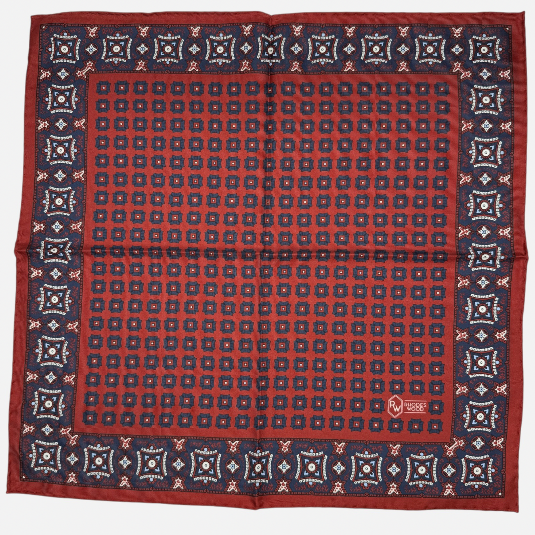 Claret pocket square with navy blue mosaics repeating across the silk. 