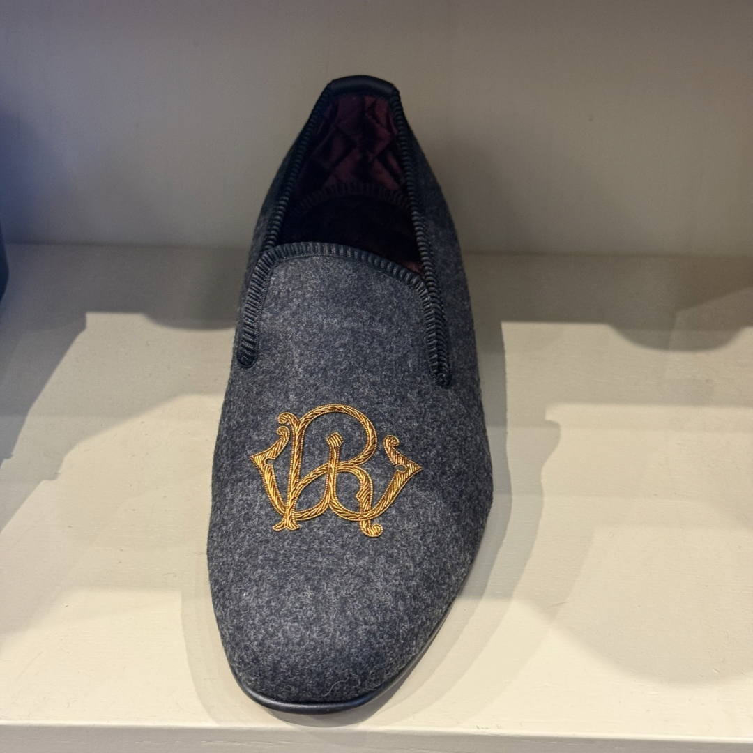 Gray slipper with gold embroidery on a white surface