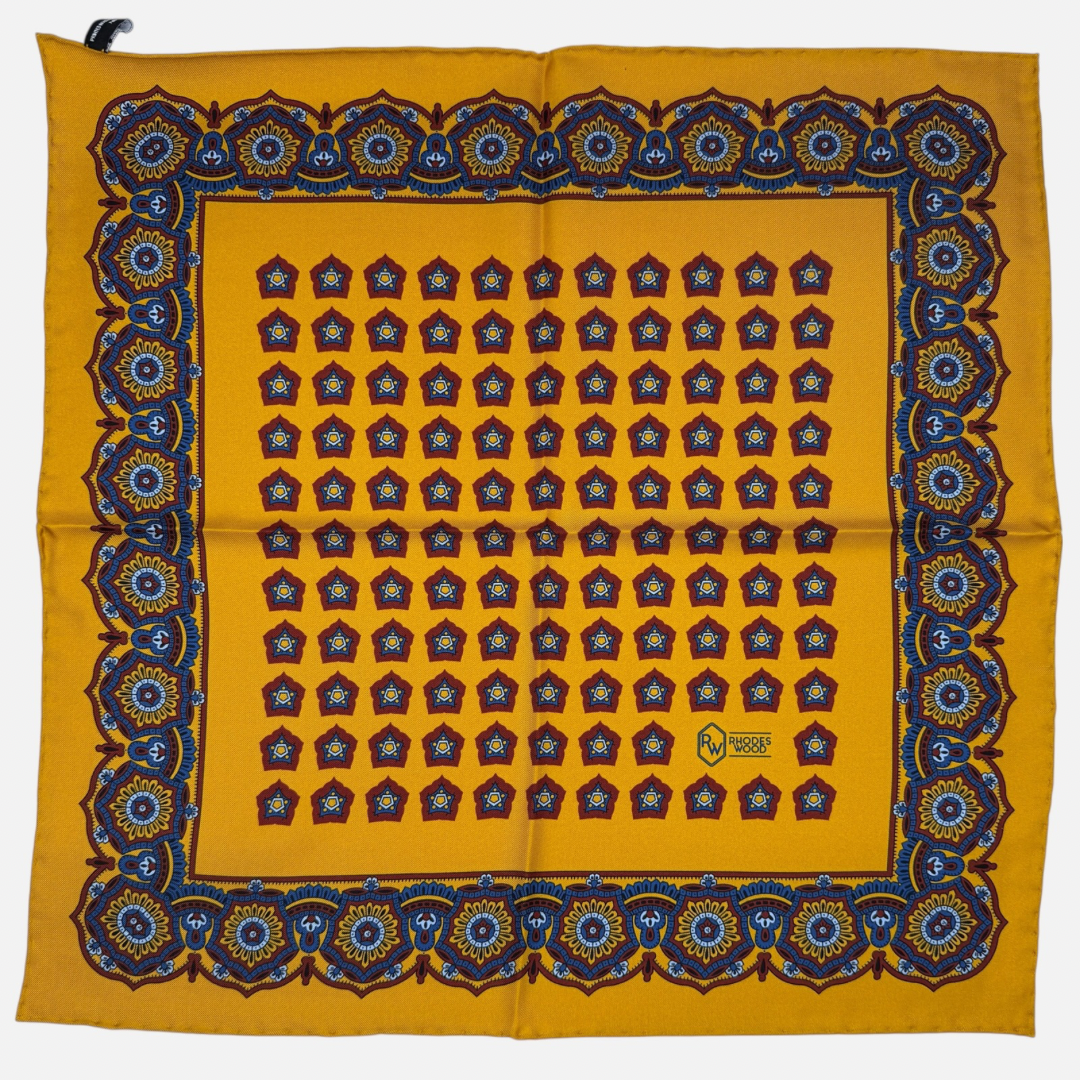 A gold pocket square with red star medallions repeating across the silk. 