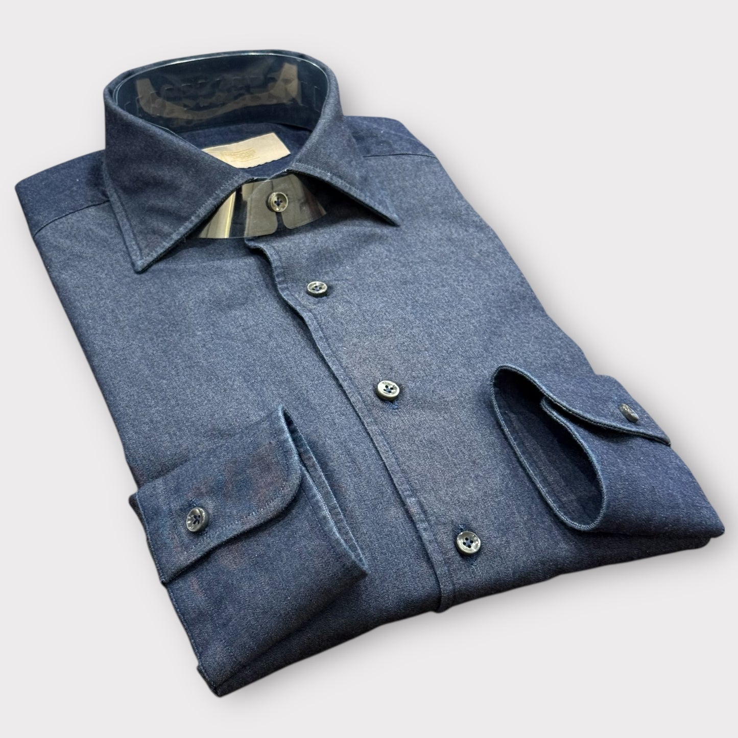 Folded blue denim shirt on a light gray background