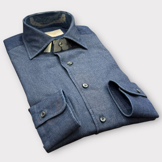 Folded blue denim shirt on a light gray background