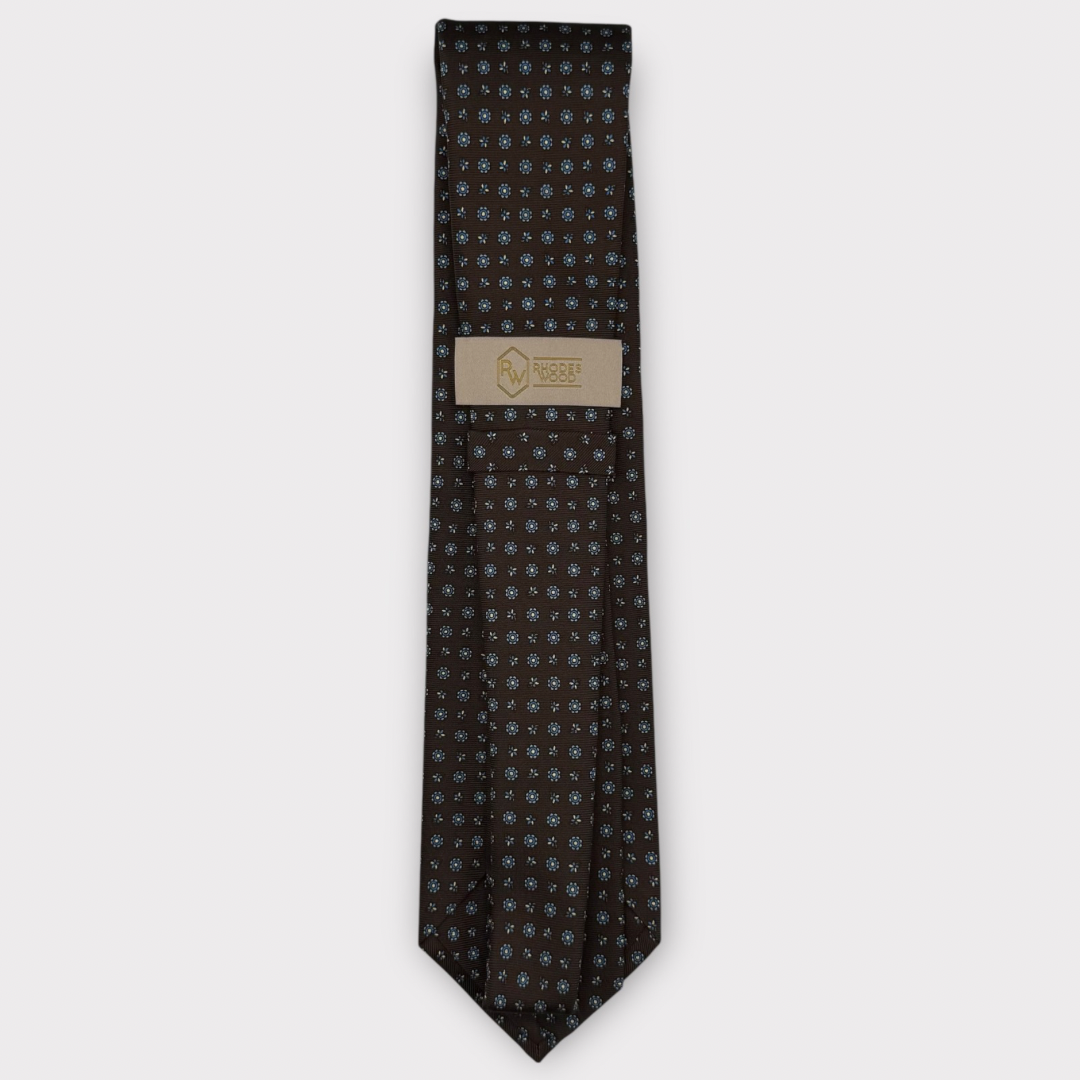 Classic silk necktie, printed in England, with a 9cm blade and 150cm length, laid flat against a plain background
