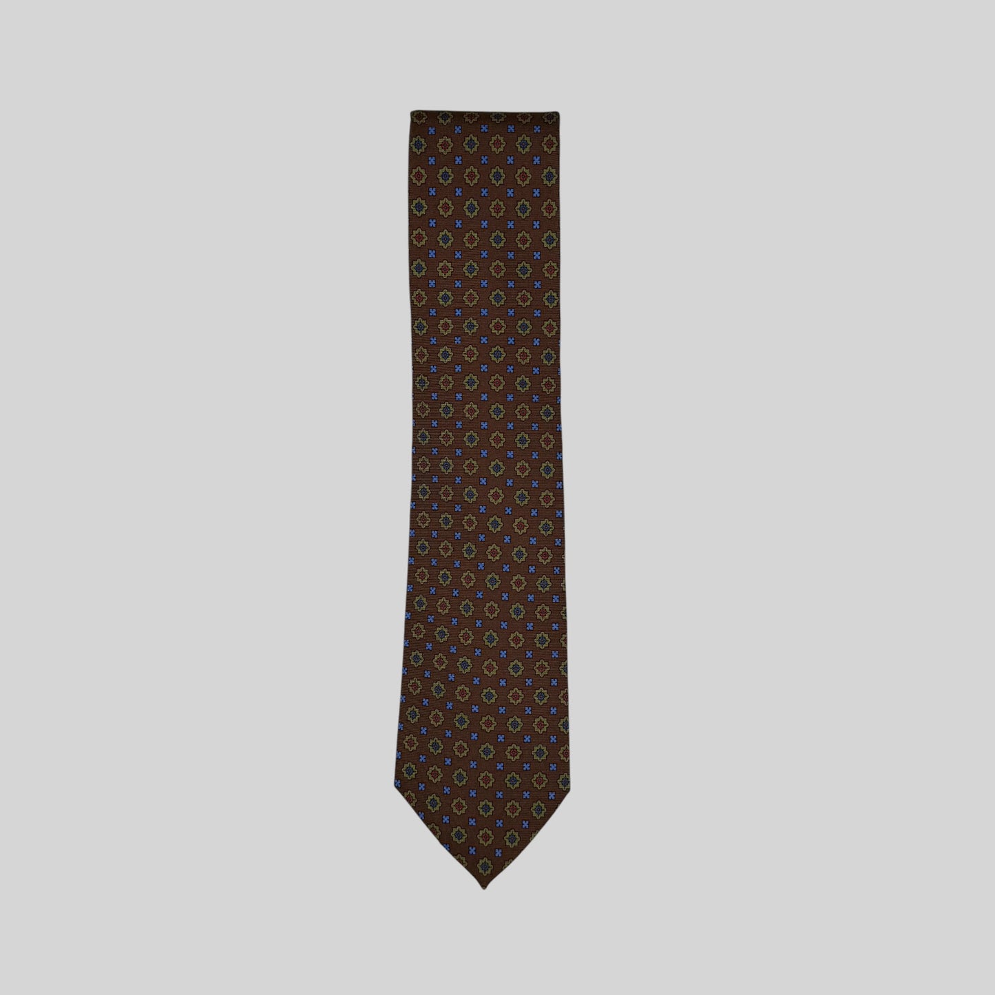 A Rhodes Wood tie in a brown base colour featuring a small medallion pattern in green, blue & red
