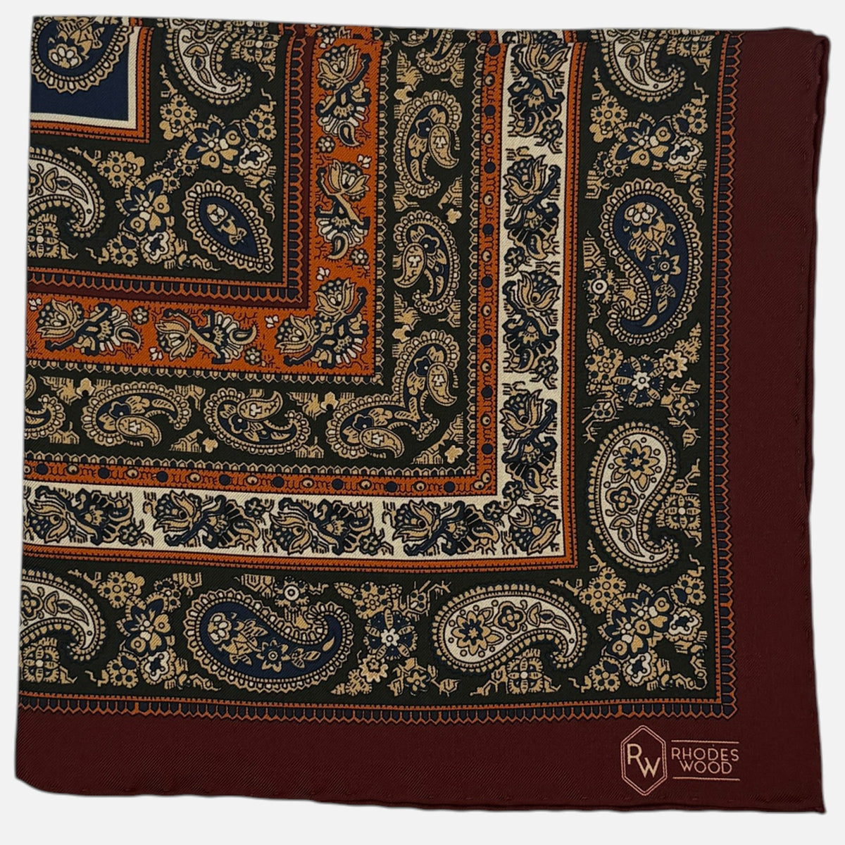 A burgundy border pocket quare with large repeating paisley design across the silk. 