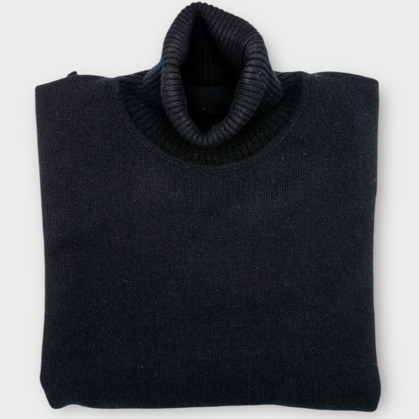 Folded black sweater on a white background
