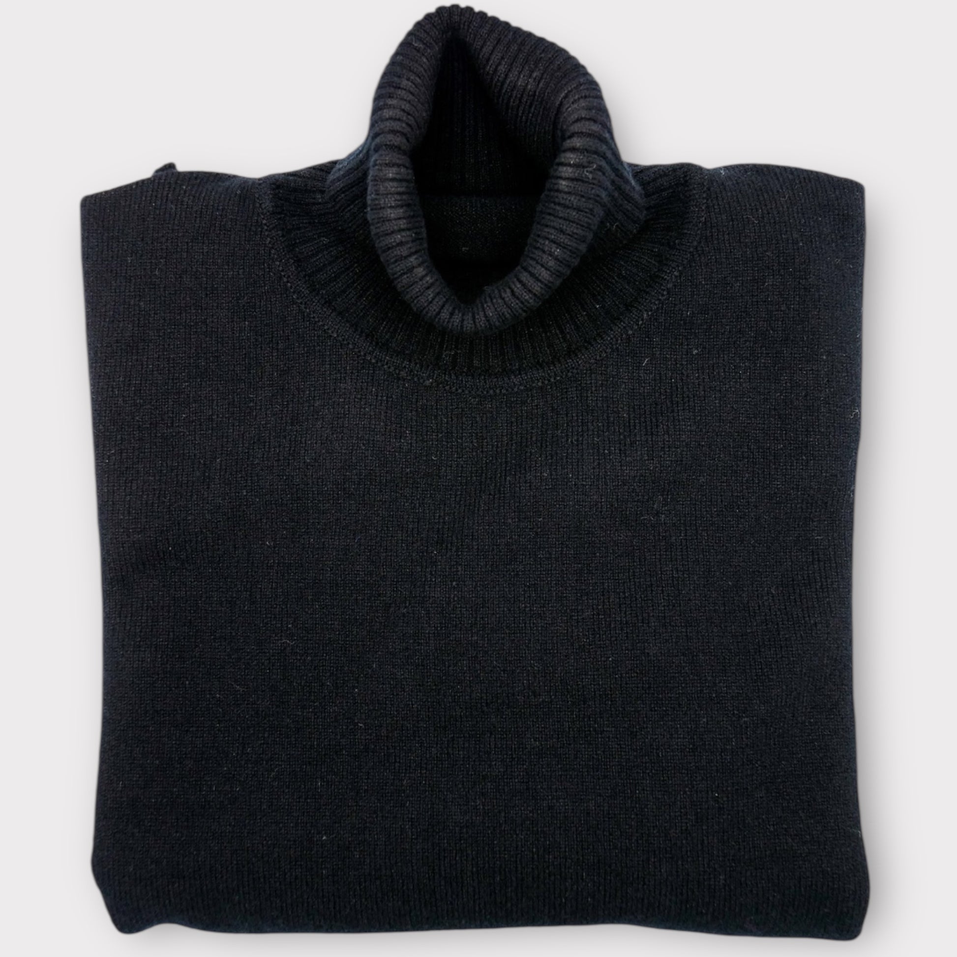 Folded black sweater on a white background