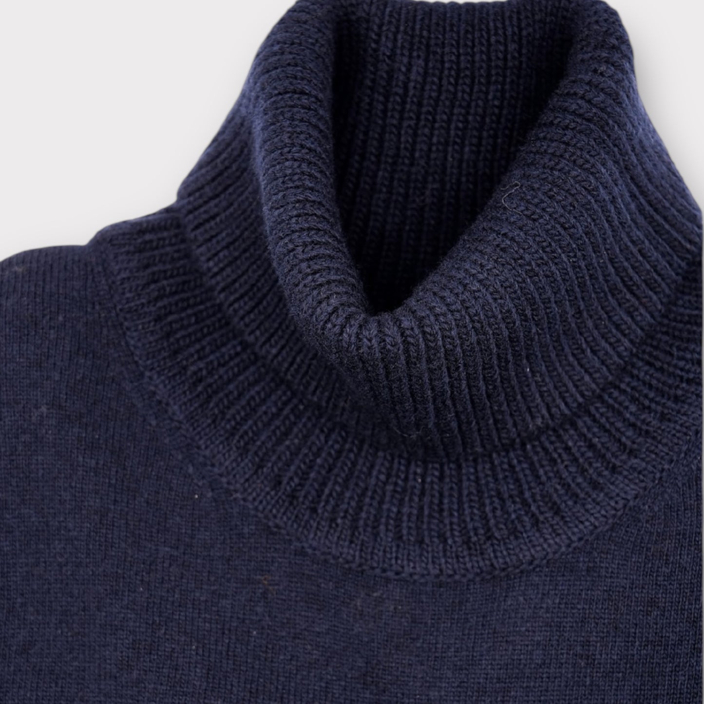 Close-up of a navy blue sweater with a ribbed collar on a white background