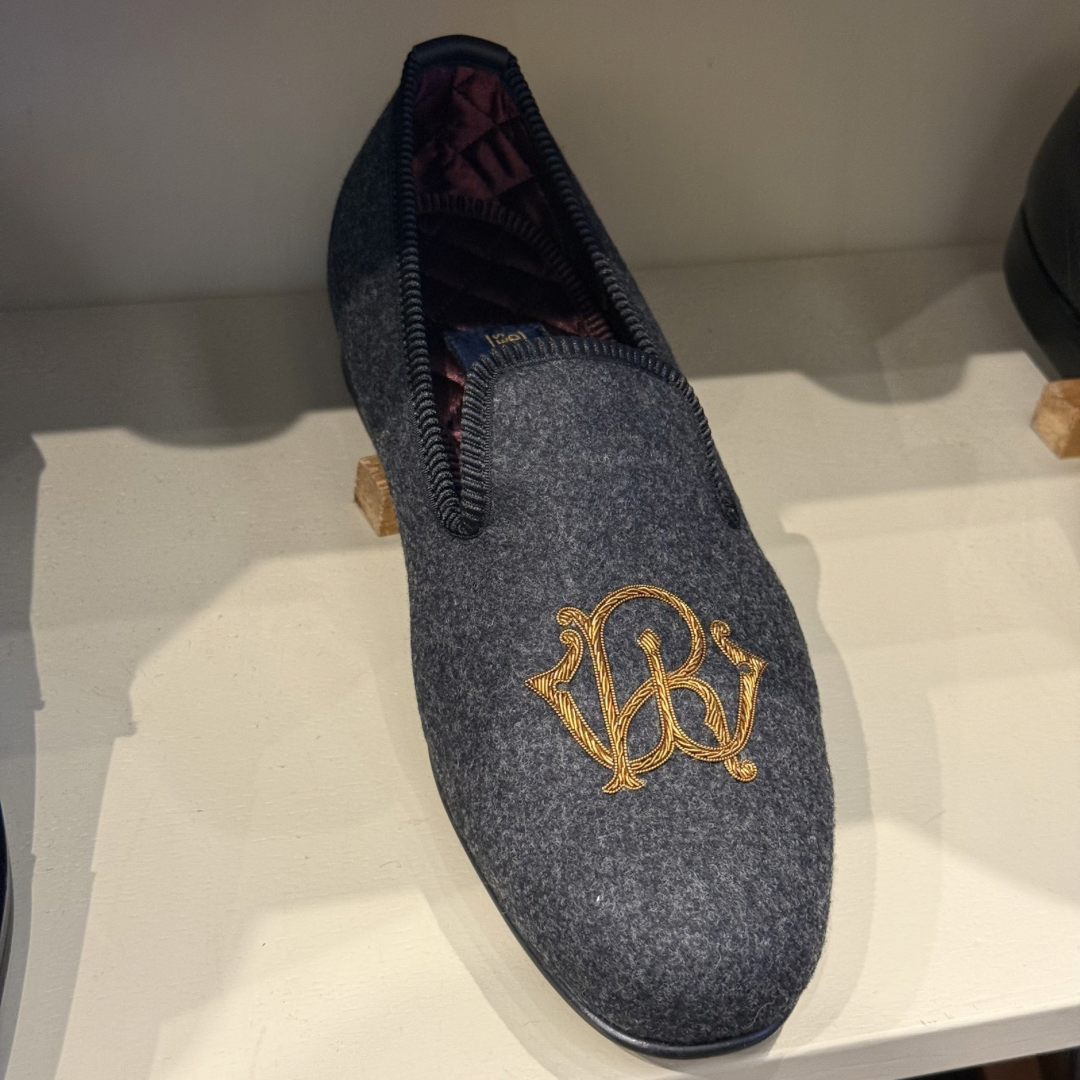 Gray slipper with gold embroidery on a white surface