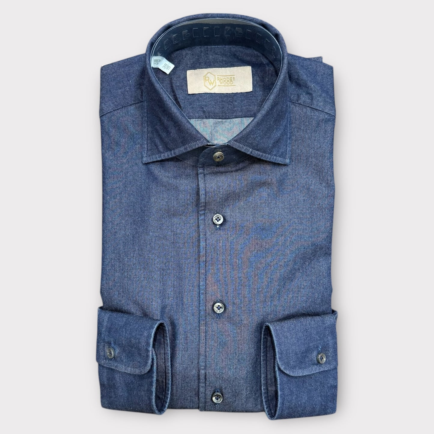 Folded blue denim shirt on a light gray background