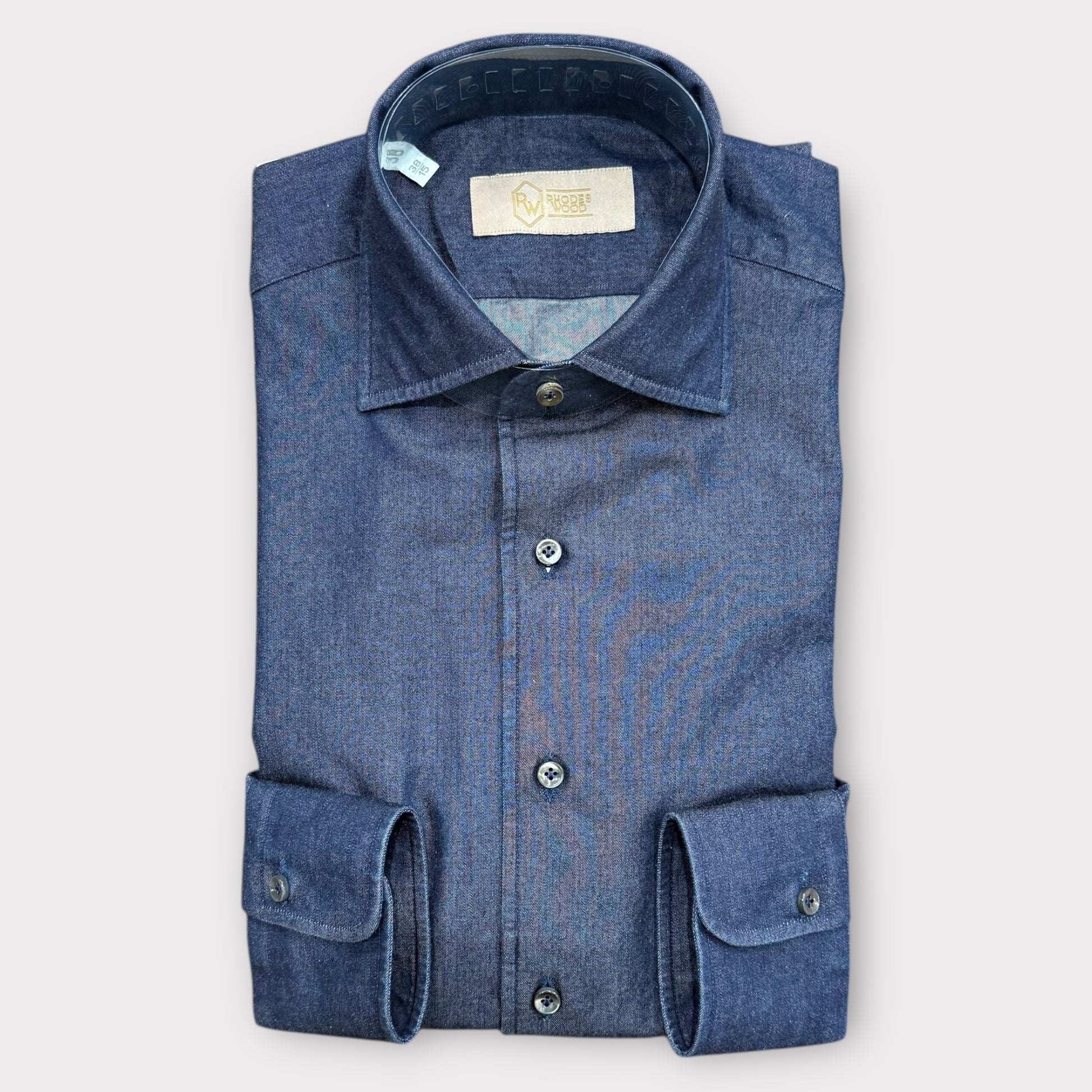 Folded blue denim shirt on a light gray background