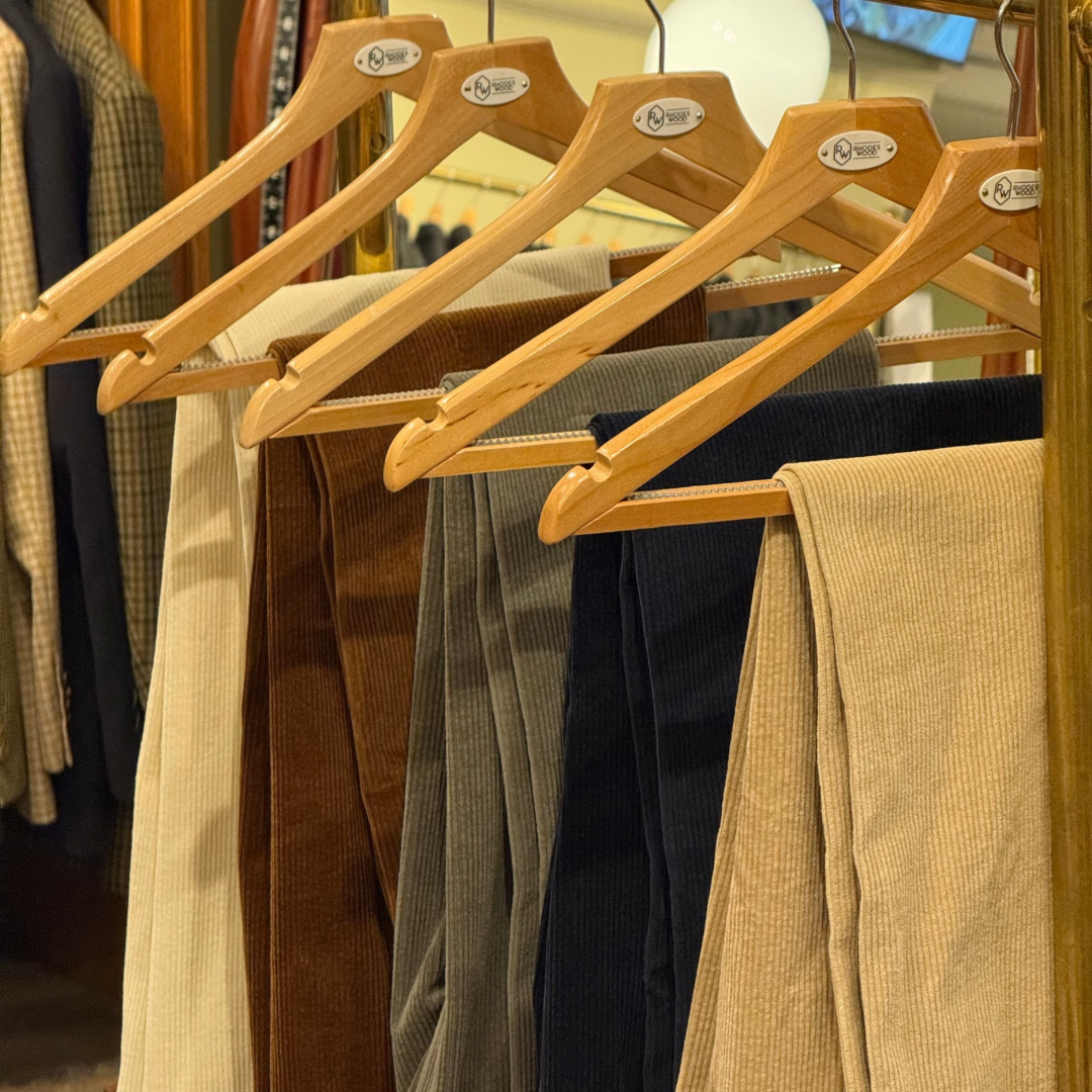 Wooden hangers with pants on a rack in a store setting