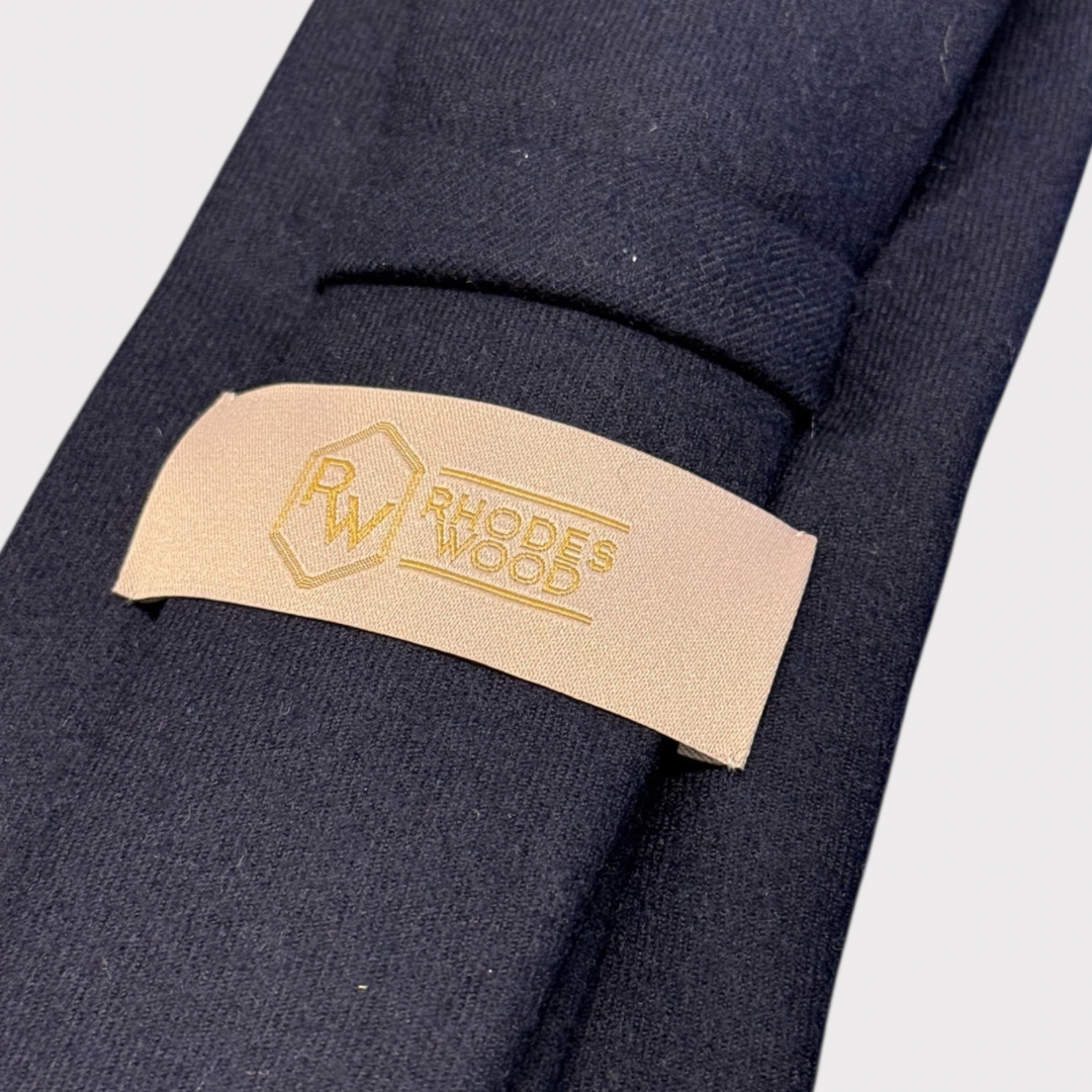 Close-up of a beige label with 'Rhodes & Wood' branding on a dark fabric background.