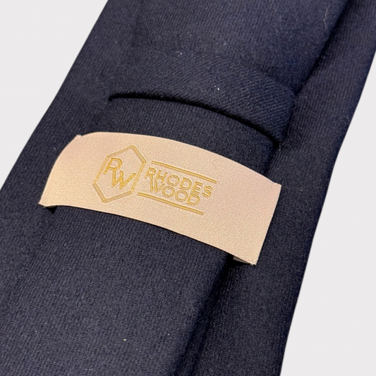 Close-up of a beige label with 'Rhodes & Wood' branding on a dark fabric background.