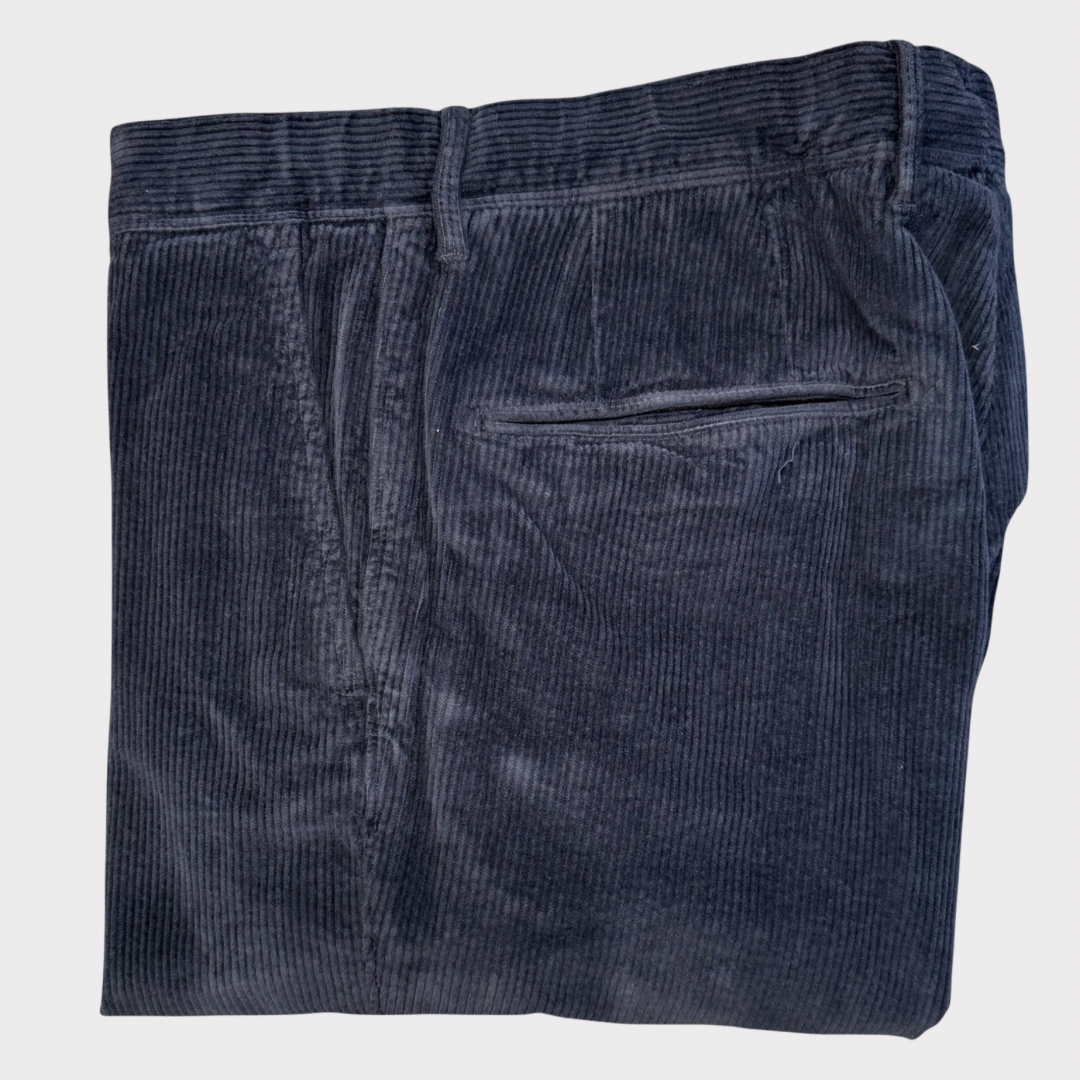 Folded dark blue corduroy trousers  on a light gray background