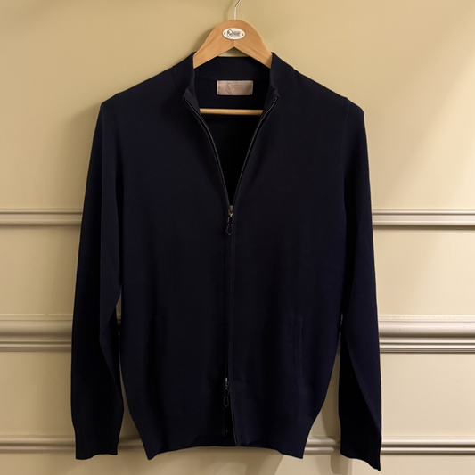 Navy blue jacket on a hanger against a beige wall.