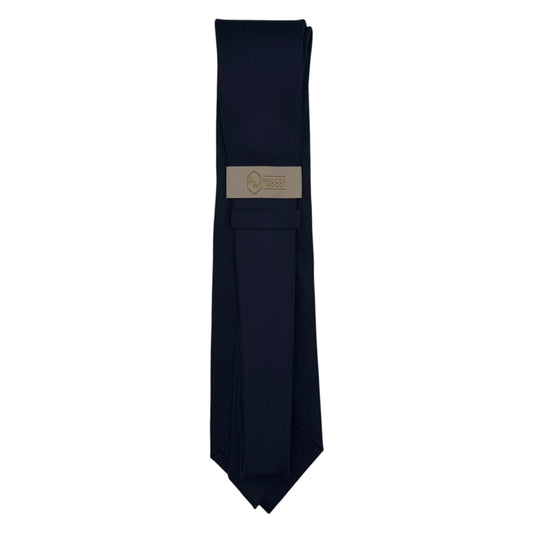 A dark navy blue necktie with a rectangular beige brand label in the center, displayed vertically against a plain white background.
